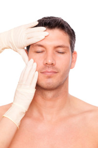 A man with his eyes closed and a pair of gloved hands touching his face